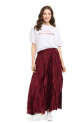 A woman modeling a white graphic t-shirt and a high-waisted, pleated burgundy maxi skirt against a plain white background.