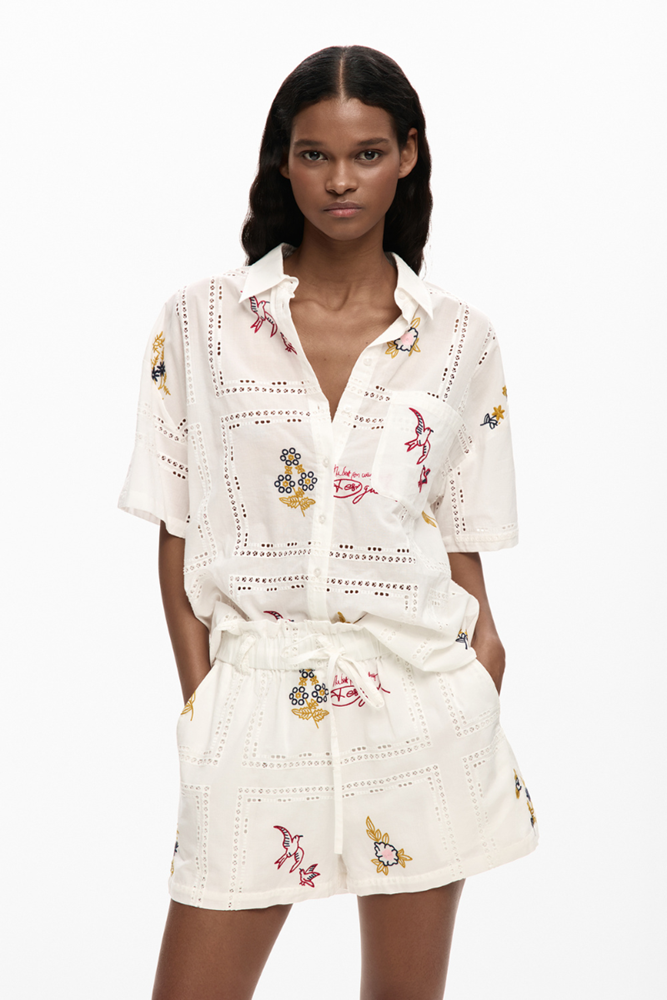 Woman wearing a white embroidered dress on a white background