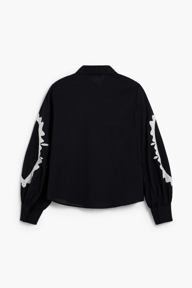 A black long-sleeve button-up shirt with white abstract graphic patterns on the sleeves, shown from the back against a plain white background.