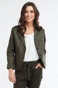 A woman modeling an olive green lightweight blazer over a white top and dark pinstriped trousers, photographed against a clean white studio background.