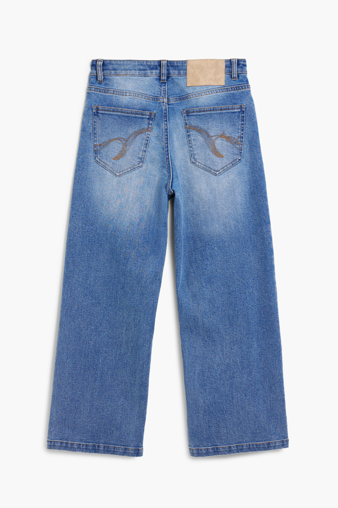 Back view of a pair of light blue denim jeans with a faded wash, showing the back pockets and a tan leather patch at the waistband, photographed on a light gray background.
