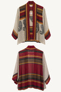Patterned poncho with a mix of red, beige, and green colors on a white background