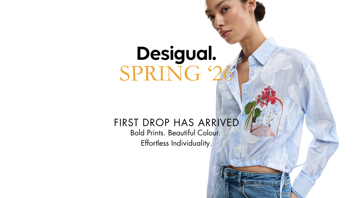 A model wearing a light blue long-sleeve button-up shirt with a floral and butterfly print, paired with blue jeans. The image features promotional text for 'Desigual Spring '26' on a clean white background.