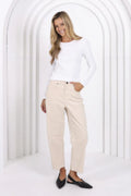 Woman wearing a white top and beige pants against a white background
