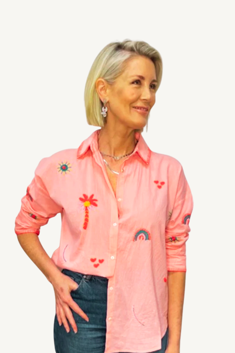 Woman wearing a pink embroidered shirt on a white background