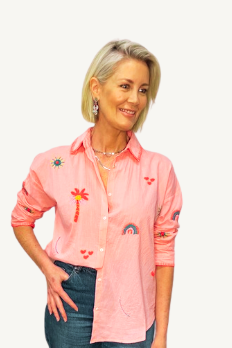 Woman wearing a pink shirt with colorful designs on a white background