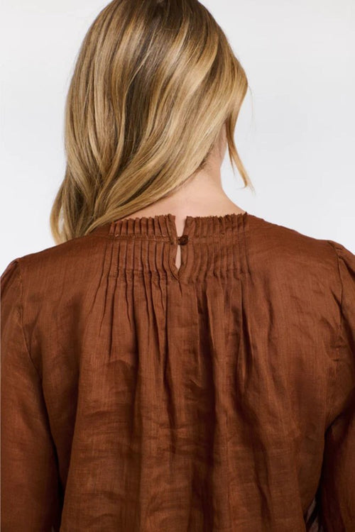 Brown blouse worn by a person with a plain background