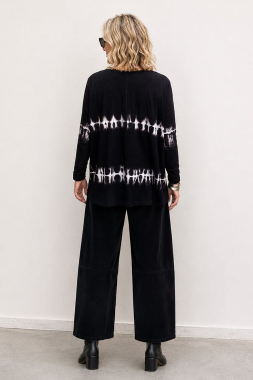 Person wearing a black outfit with tie-dye sleeves against a white background