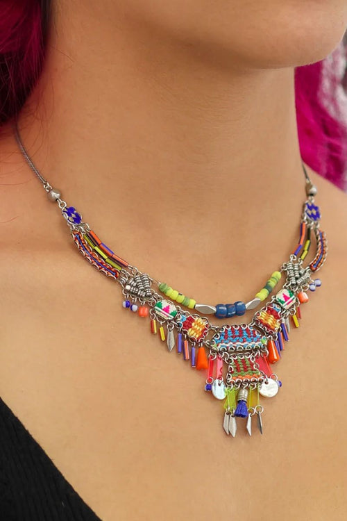 Colorful beaded necklace worn by a person with pink hair.