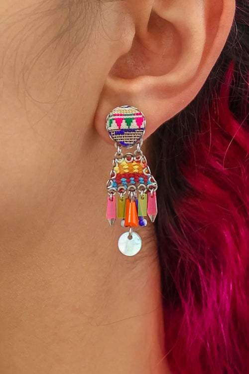 Multicolored earrings worn by a person with red hair.