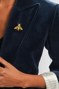 Navy blazer with a gold bee pin worn by a person.