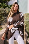 Woman wearing a brown poncho with white floral patterns outdoors.