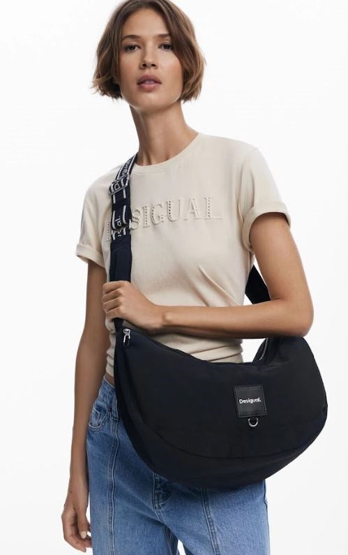 Woman holding a black shoulder bag against a white background