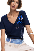 Woman wearing a navy blue t-shirt with a butterfly design on a white background