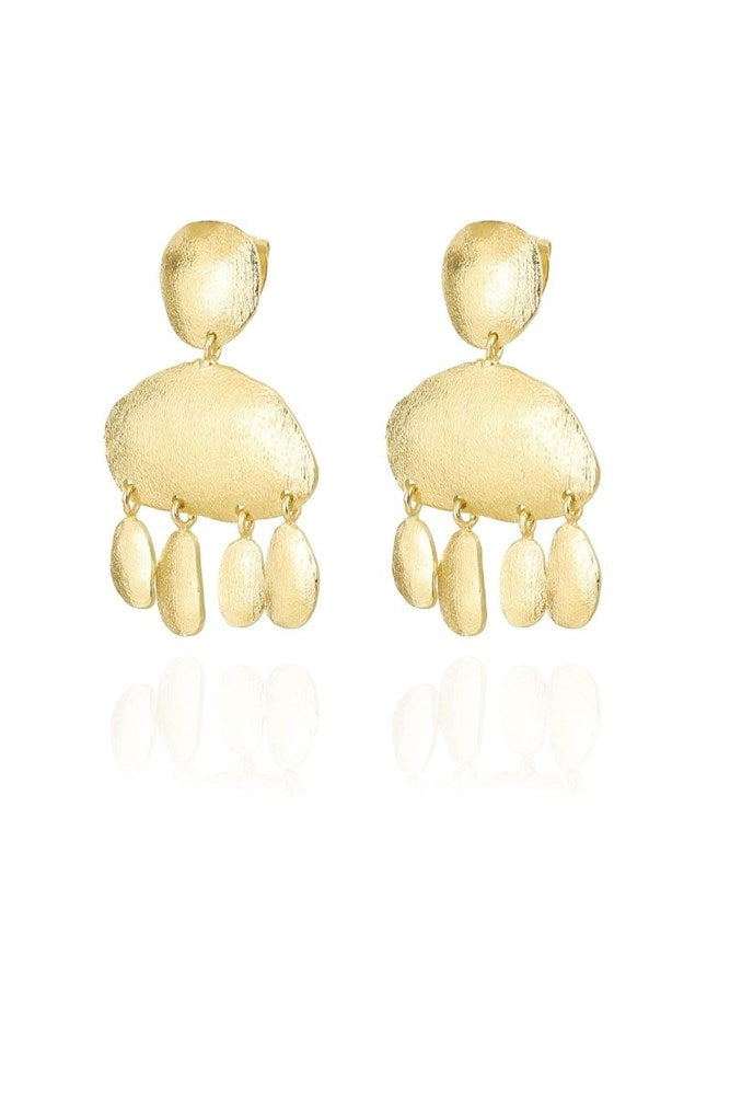 A pair of gold-toned dangle earrings with a textured, organic abstract shape and small hanging teardrop charms, shown on a clean white background with a soft reflection below.