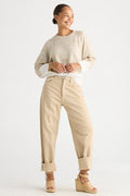 A woman modeling a light beige knit long-sleeve top and matching beige wide-leg cropped pants with rolled cuffs, paired with beige wedge sandals, against a plain white studio background.