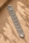 Metal chainmail bracelet on a textured beige surface