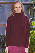 Woman wearing a maroon cable knit sweater in an indoor setting with plants.