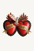 Decorative wall art with two red hearts, a dove, and Spanish text on a white background