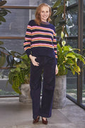 Woman wearing a striped sweater and velvet pants standing in a room with plants.
