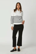 Woman wearing a white and black striped sweater with black pants on a white background