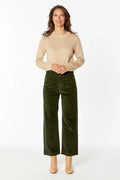 Woman wearing a beige sweater and green pants on a white background
