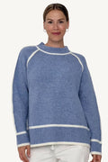 Woman wearing a blue sweater with white trim on a white background