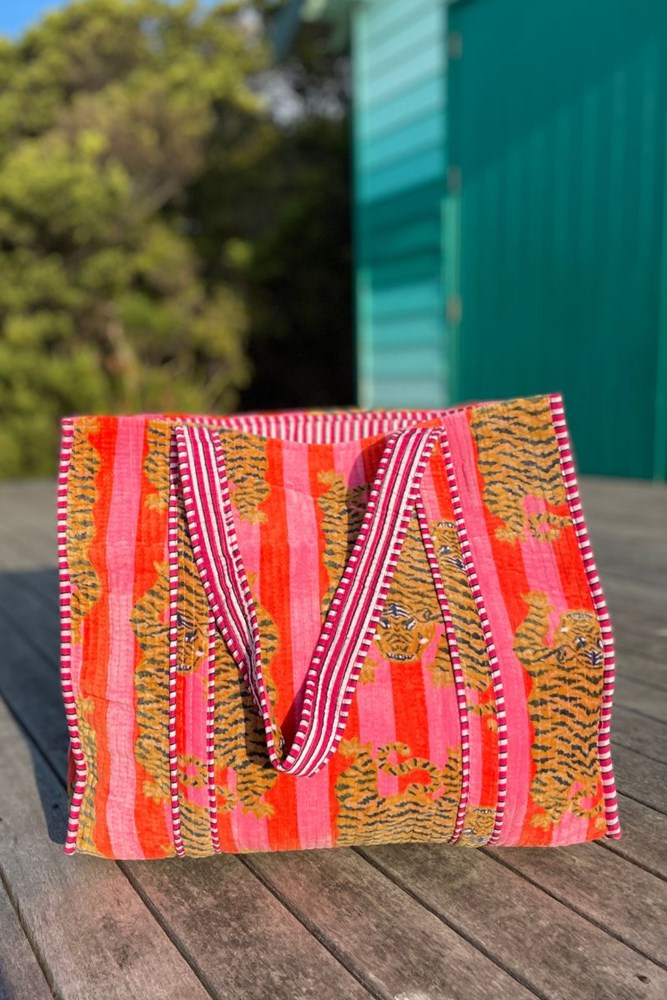 Colorful patterned bag with pink straps on a wooden surface