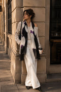 Woman in a stylish outfit leaning against a building wall.