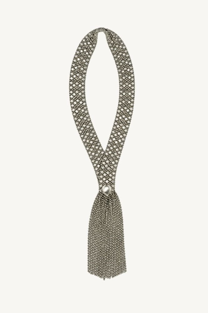 A silver-toned beaded tassel necklace with a geometric pattern, displayed on a solid off-white background.